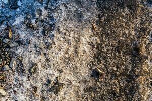 nieve cubrir y hielo en el congelado suelo con piedras y arena. sn foto