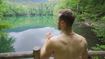 Drinking water in nature, muscular man is drinking water. video