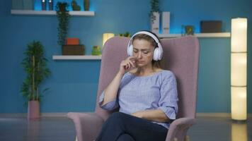 Woman listening to music with headphones is unhappy and sad. video