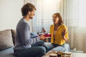 Portrait of young happy couple. Man is giving gift to his woman. photo