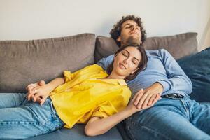 Portrait of young happy couple at home. They are relaxing at sofa. photo