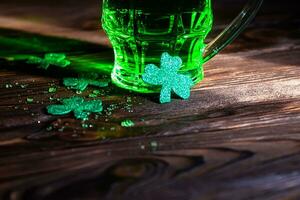 trébol hojas con salpicaduras de frío cerveza en un de madera mesa. un vaso de verde tradicional cerveza en S t. patrick's día en un irlandesa pub foto