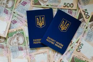 Two international passport of Ukrainians lie on pile of money from five hundred-pound banknotes. Passports for departure to Europe without visas. Visa-free regime for Ukraine. photo