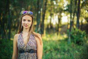 Beautiful girl in a light sarafan with developing hair on forest background. Girl is smiling standing. photo