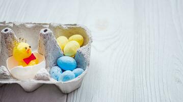 A small chicken in a paper egg tray next to a pile of yellow and blue eggs. Easter in Ukraine. Homesickness. Immigrants and migrants from Ukraine celebrate Easter photo