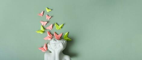 Plaster head with butterflies on a green background. Mental health concept banner. photo