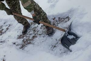 hombre borra el yarda de nieve con pala. pesado nevada en invierno. alto nivel de nieve. Nevado ventisquero. foto