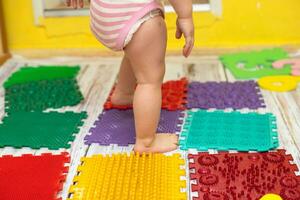 child walking on orthopedic massage puzzle floor mat photo