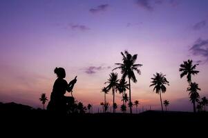 silueta de un mujer tomando un foto de palma arboles a puesta de sol