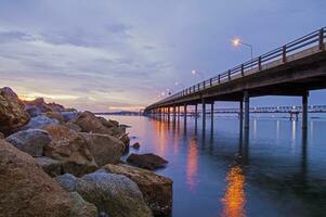 a bridge over water with rocks and lights photo