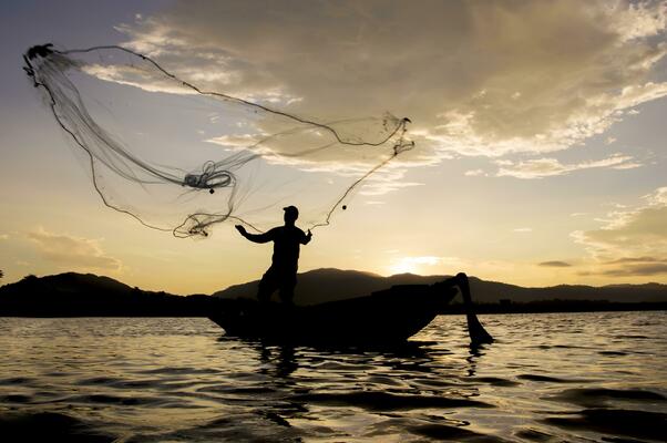 Fisherman with a wicker basket and fishing net goes to the sea. Picturesque  landscape of Thailand coast Stock Photo