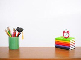 oficina escritorio mesa, estudiante creativo escritorio con vistoso papelería, de tapa dura libro,graduación sombrero, rojo alarma. Copiar espacio para texto, espalda a escuela, educación concepto foto