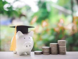 Piggy bank with graduation hat and stack of coins. The concept of saving money for education, student loan, scholarship, tuition fees in future photo