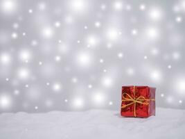 Red gift box with shiny light for Christmas and New Year holidays background, Winter season, falling snow, Copy space for Christmas and New Year holidays greeting card. photo