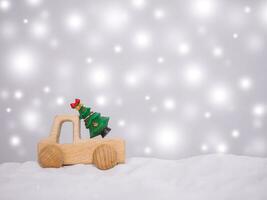 Wooden toy car and Christmas tree with shiny light for Christmas and New Year holidays background, Winter season, falling snow, Copy space for Christmas and New Year holidays greeting card. photo