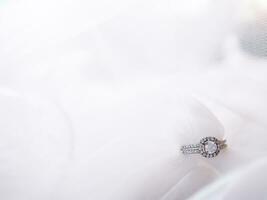 Diamond engagement wedding rings on bridal veil. Wedding accessories, Valentine's day and Wedding day concept. photo
