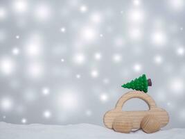 Wooden toy car and Christmas tree with shiny light for Christmas and New Year holidays background, Winter season, falling snow, Copy space for Christmas and New Year holidays greeting card. photo