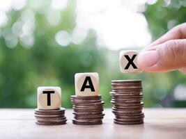 Wooden blocks with the word TAX on stack of coins, The concept of saving money for payment tax in future photo