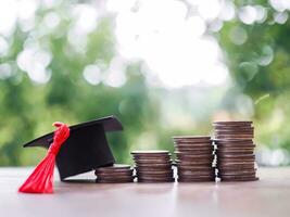 Graduation hat on stack of coins. The concept of saving money for education, student loan, scholarship, tuition fees in future photo