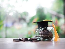 Glass bottle with graduation hat and stack of coins. The concept of saving money for education, student loan, scholarship, tuition fees in future photo