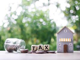 Wooden blocks with the word TAX on stack of coins and Miniature house. The concept of payment tax for house, Property investment, House mortgage, Real estste. photo