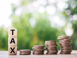 Wooden blocks with the word TAX and stack of coins, The concept of saving money for payment tax in future photo