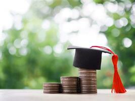 Graduation hat on stack of coins. The concept of saving money for education, student loan, scholarship, tuition fees in future photo