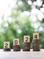 Wooden block with number 2024 on stack of coins. The concept of saving money, Financial, Investment and Business growing in new year 2024. photo