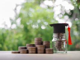 Glass bottle with graduation hat and stack of coins. The concept of saving money for education, student loan, scholarship, tuition fees in future photo