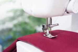 Close up of sewing machine working with red fabric,  stitch new clothing. photo