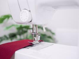 Close up of sewing machine working with red fabric,  stitch new clothing. photo