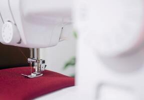 Close up of sewing machine working with red fabric,  stitch new clothing. photo