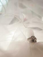 Diamond engagement wedding rings on bridal veil. Wedding accessories, Valentine's day and Wedding day concept. photo