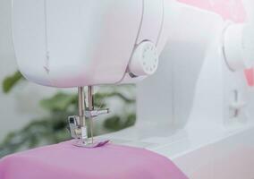 Close up of sewing machine working with purple fabric,  stitch new clothing. photo