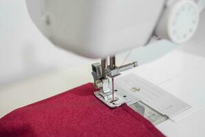 Close up of sewing machine working with red fabric,  stitch new clothing. photo