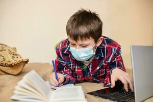 sick boy wearing a protective medical mask does his homework while sick photo