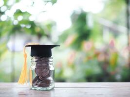 Close up money in the glass bottle with graduation hat. The concept of saving money for education, student loan, scholarship, tuition fees in future photo