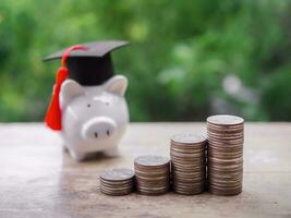 Piggy bank with graduation hat and stack of coins. The concept of saving money for education, student loan, scholarship, tuition fees in future photo