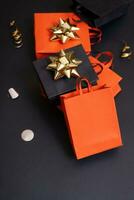 Black friday sale, shopping concept. Red and black paper shopping bags with decorations on black background. photo