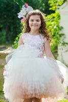 hermosa niña en un elegante rosado vestir saltos cerca columpio decorado con flores niño celebra cumpleaños 8 años. hermosa flores primavera tema columpio en jardín foto