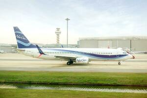 Bangkok City, BKK, 2020 - Side view of New gen aircraft landing and slow running to terminal parking on airport runway under bright blue sky with cloud. photo