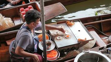 Ratchaburi City, RB, 2022 - Sellers selling Thai snack on boats, Ancient travel destination of Thailand photo