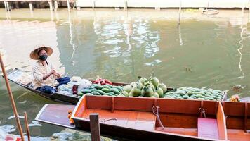 Ratchaburi City, RB, 2022 - Sellers selling mango and pomelo on boats at ancient travel destination of Thailand Damnoen saduak flating market, Ratchaburi Thailand. photo