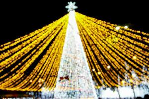 borroso y bokeh de brillante Navidad árbol Encendiendo en noche hora antecedentes. foto