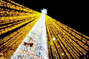 Look up view blurred and bokeh of Christmas tree lighting on night time background. photo