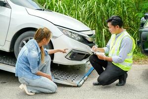 Closeup insurance company officers post a list of repairs on work list clipboard according sufferer woman point out the damage on her car background. photo