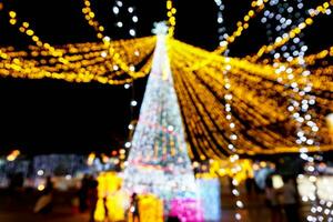 borroso y bokeh de Navidad fiesta Encendiendo con personas en noche hora antecedentes. foto