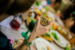 A glass filled with white wine in hand girl. Festively decorated table in the restaurant. photo