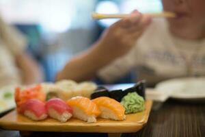 chico comiendo Sushi con palillos. foto