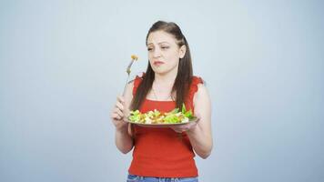 Person looking at vegetable on fork with unhappy expression. Difficulty dieting. video